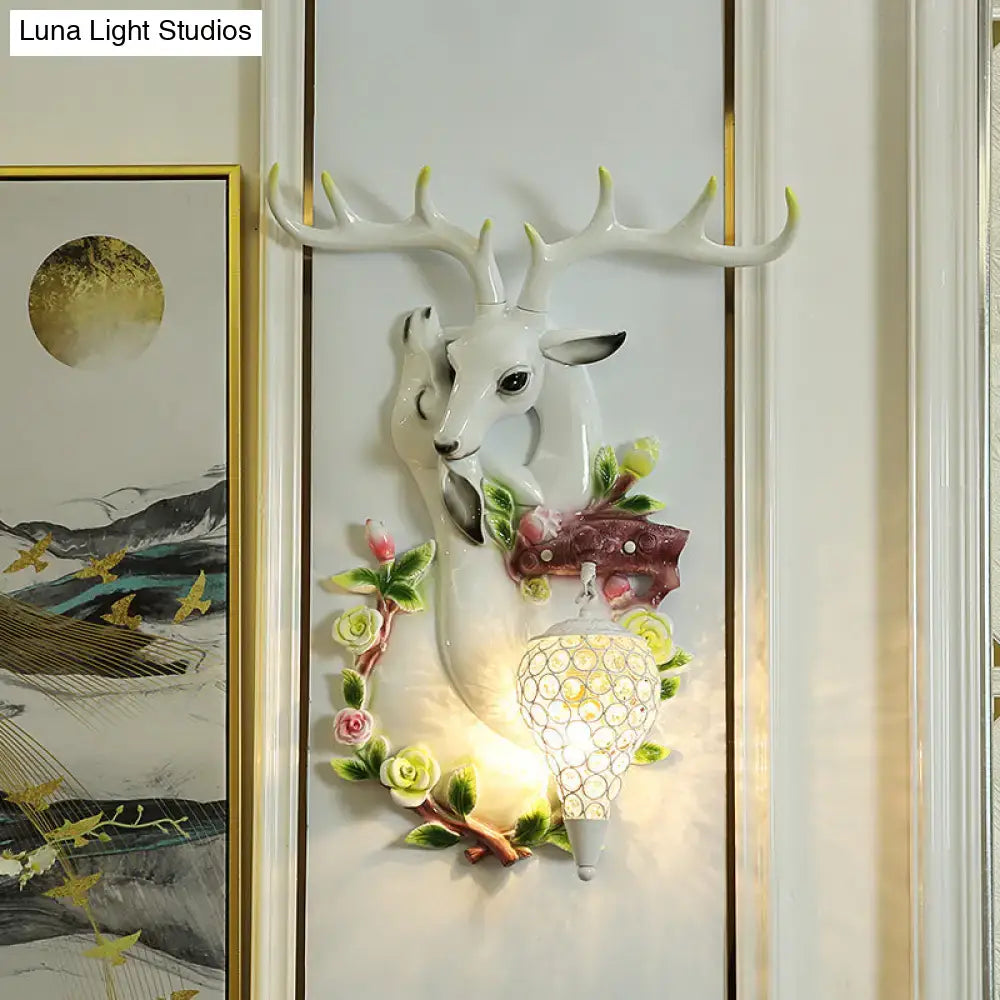 White ceramic deer head accent wall sconce with floral details and crystal-encrusted lampshade for bedroom lighting