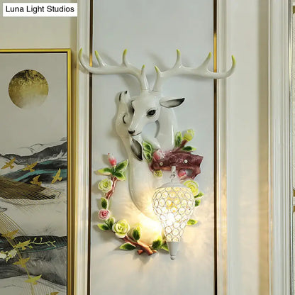 White ceramic deer head accent wall sconce with floral details and crystal-encrusted lampshade for bedroom lighting