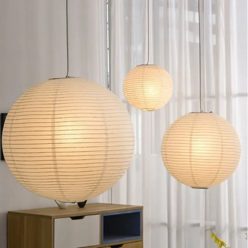 Three warm glowing vintage akari rice paper pendant lights with vertical ribbed texture for bedroom or living room