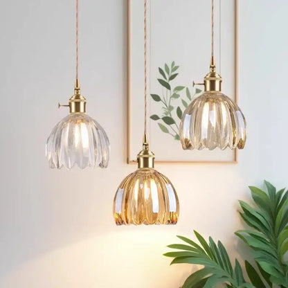 Three elegant vintage amber and clear glass pendant lights with gold-toned metal fixtures and iron finish for dining room