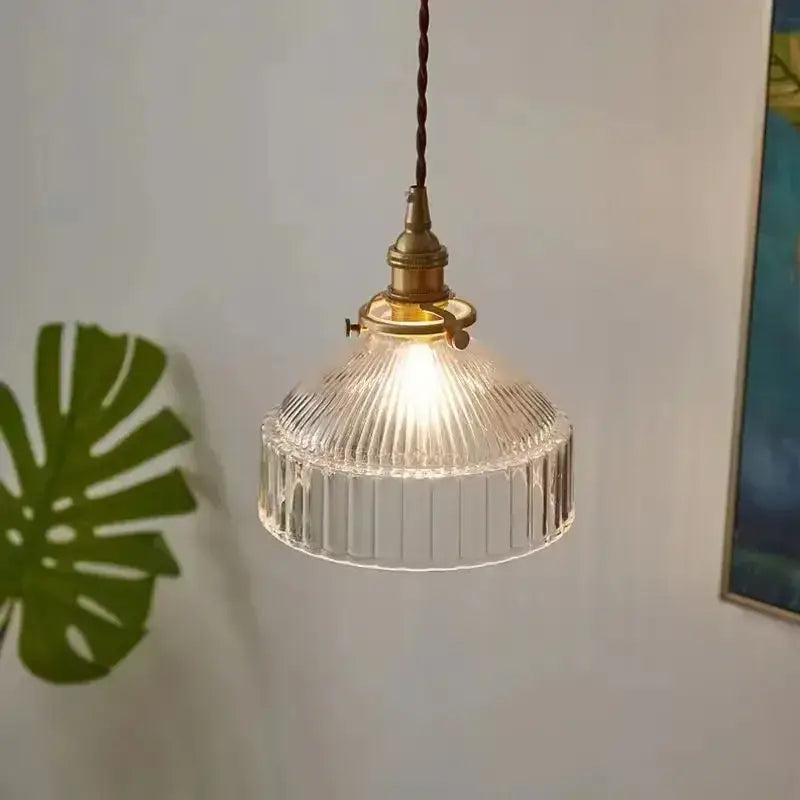 Vintage amber colored glass pendant light with vertical ridges featuring clear ribbed glass and brass fixture