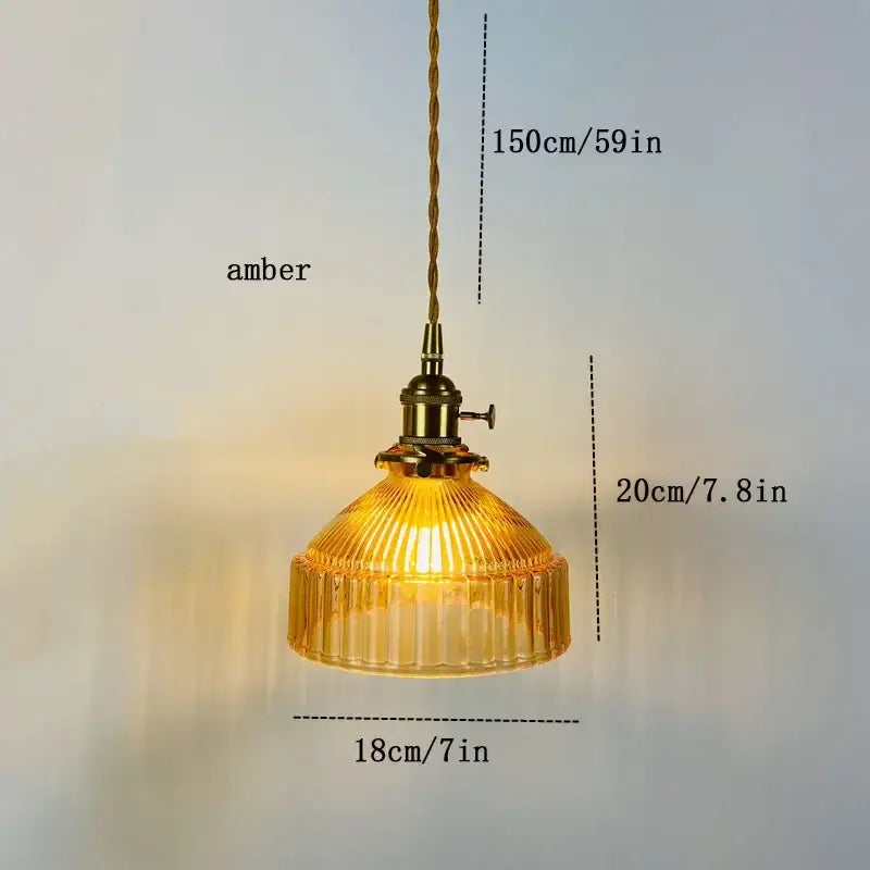 Vintage amber colored glass pendant light with vertical ridges brass hardware and twisted cord suspension for dining room
