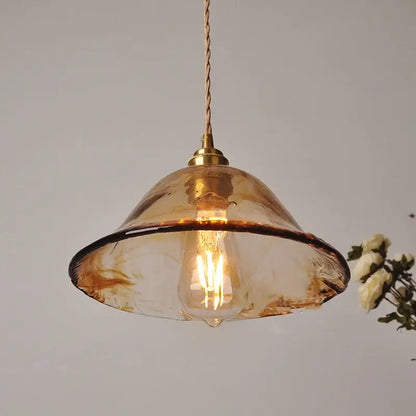 A vintage amber glass adjustable pendant light with brass fixture and twisted cord for dining room lighting