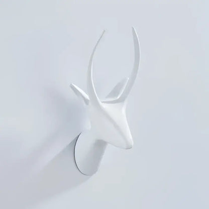 White ceramic deer head wall decor with minimalist antlers paired with vintage brass robe hooks for bathroom decorbites decor