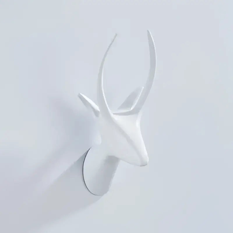 White ceramic deer head wall decor with minimalist antlers paired with vintage brass robe hooks for bathroom decorbites decor