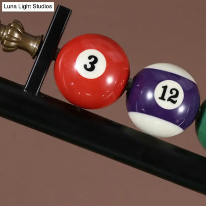 Red and purple pool balls with white numbers rest on a black rack under decorbites™ vintage style black metal ceiling light ideal for billiard room