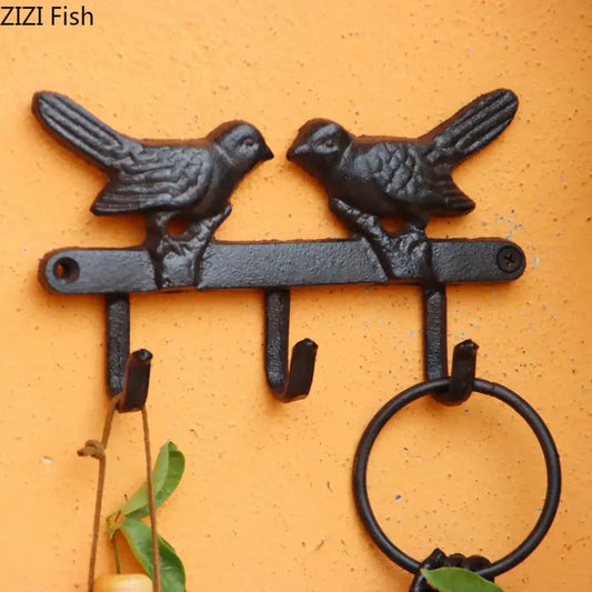Vintage black cast iron bird hook wall shelf with two birds perched on a bar and three hooks for entryway storage