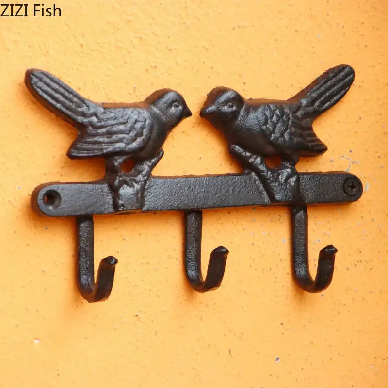 Vintage black iron wall shelf featuring a bird hook wall design with two detailed bird figures and three hooks for entryway storage