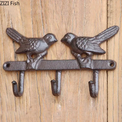 Dark brown cast iron bird hook wall shelf with two detailed birds and three hooks for entryway storage