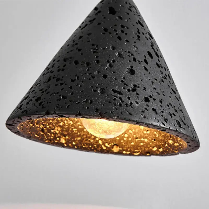 Vintage black travertine led pendant light featuring a textured volcanic stone exterior and warm gold interior lining