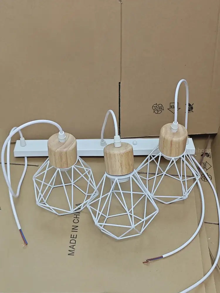 Set of three white geometric iron cage pendant lights with natural wood tops ideal for dining room lighting