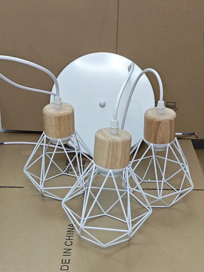 Three white geometric wire pendant lights with natural wood caps complement vintage black wood and iron cage pendant light