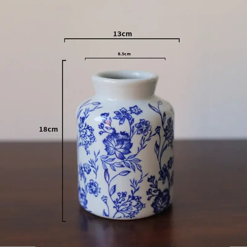 A small white porcelain vase with intricate blue floral patterns and a narrow neck for living room decorbites blue white decor