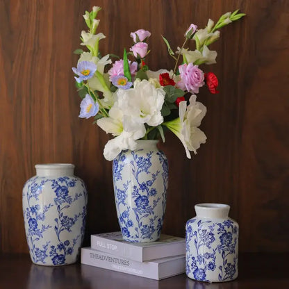 A tall blue white porcelain vase with intricate floral patterns from decorbites holds a vibrant mixed flower bouquet