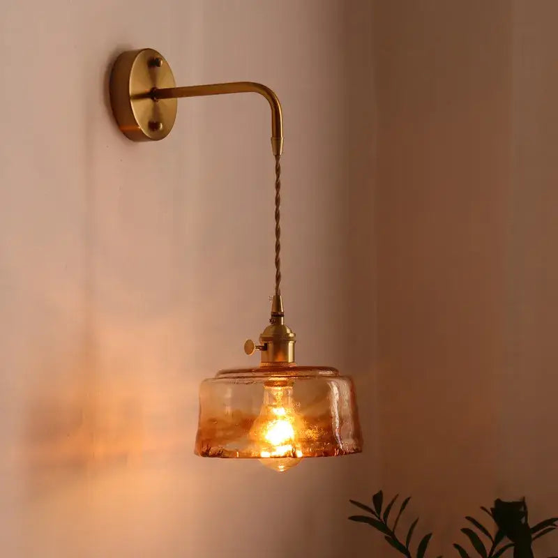 A warm-toned vintage brass wall sconce with twisted cord and amber glass copper led shade for bedroom light