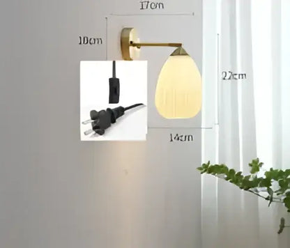 Vintage brass and amber glass led wall lamp with a curved arm and oval frosted glass shade for bedroom sconce lighting