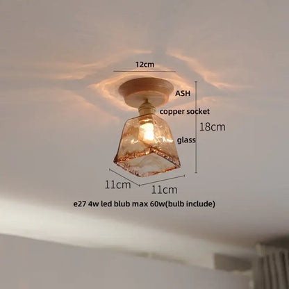 A warm-toned clear glass led ceiling light with faceted glass, copper socket, and wooden base for bedroom decorbites