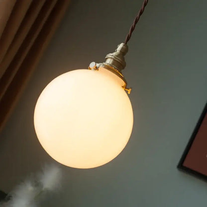 Vintage brass pendant light with warm-toned cream glass ball and twisted brown cord for kitchen decorbites cream glass