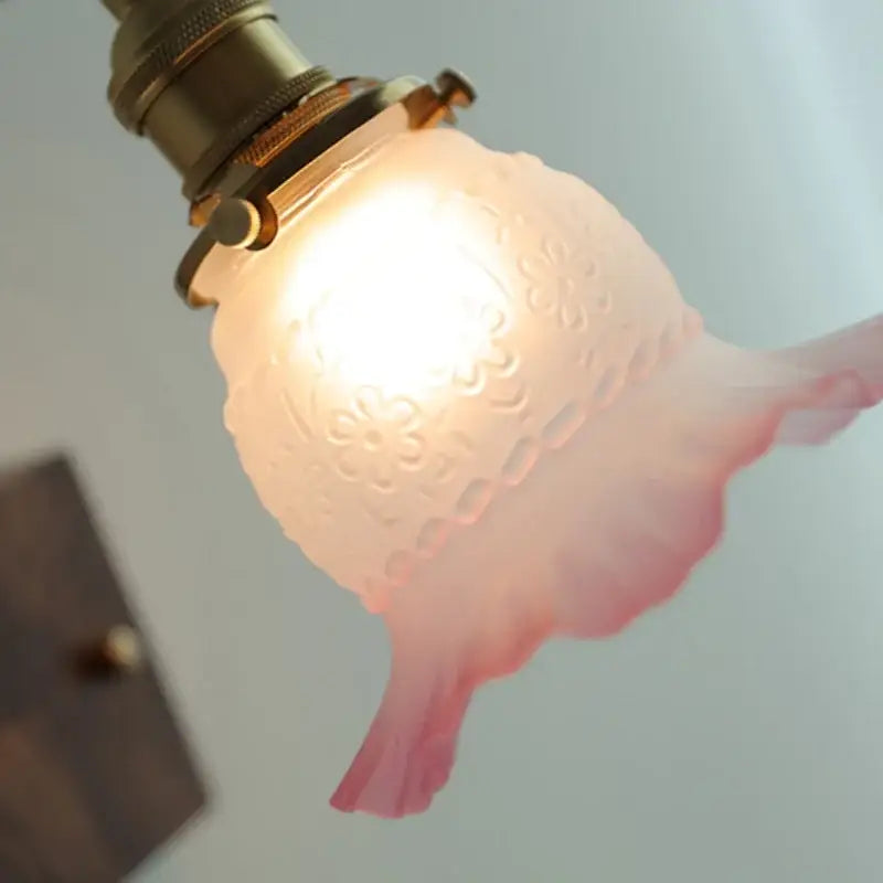 Vintage brass and glass pink led wall sconce with delicate pink frosted lampshade and intricate floral etching for bedroom