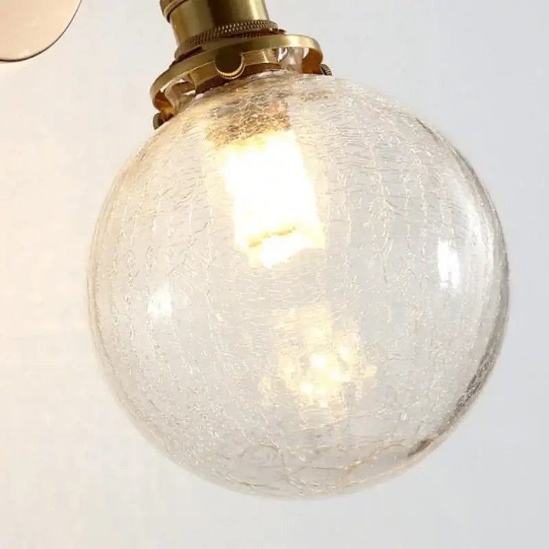 Vintage brass clear glass wall lamp with warm-toned crackled glass globe and pull chain switch for bathroom use