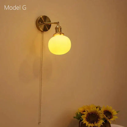 Brass-finished decorbites ceramic sconce lamp with frosted glass globe and pull chain for bedroom reading light