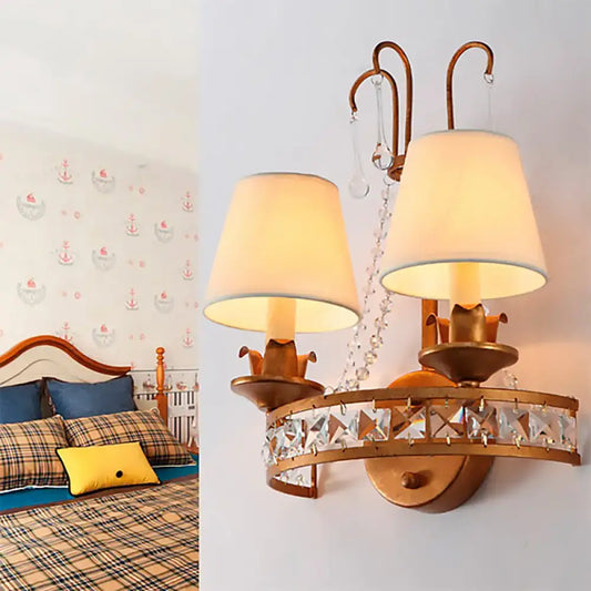 Vintage brass finish wall lamp with gold-toned frame, cream fabric shades, and decorative crystal band for bedroom use