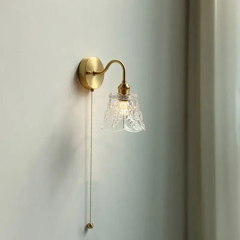 A vintage brass wall sconce with a floral etched glass led shade and elegant curved arm for glass led bathroom decorbites