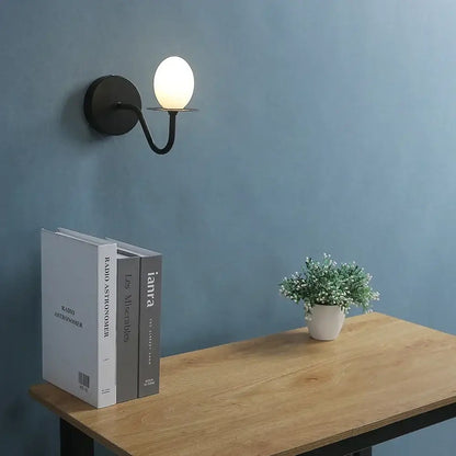 Black metal wall lamp with frosted white glass egg mini shade designed as vintage bedroom sconce