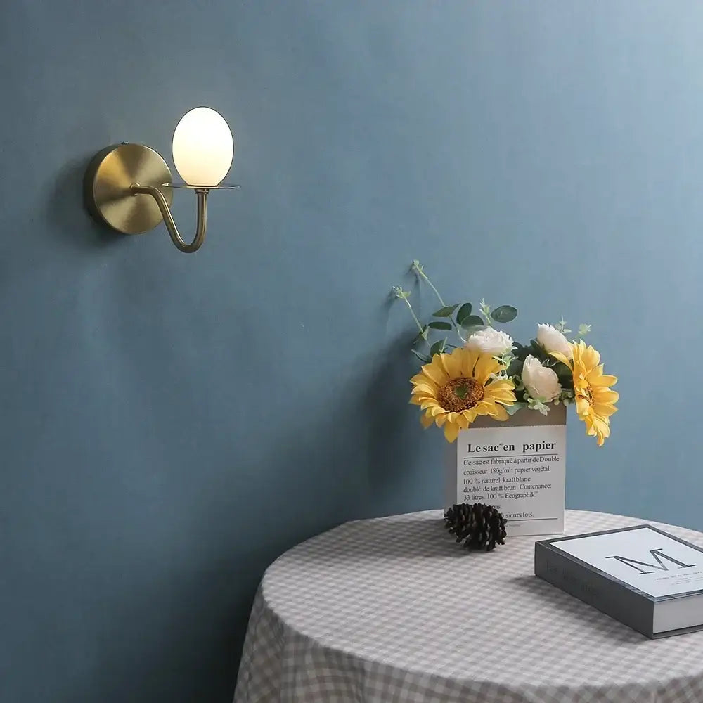 Vintage brass wall lamp with oval frosted glass egg mini shade designed as an elegant bedroom sconce