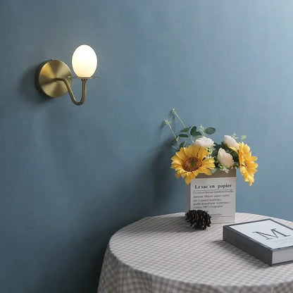 Vintage brass wall lamp with oval frosted glass egg mini shade designed as an elegant bedroom sconce