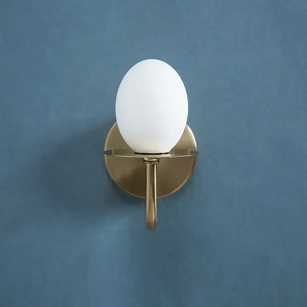 Vintage brass glass egg mini wall lamp with a matte white opal glass globe and brushed brass base for bedroom sconce use