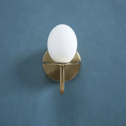 Vintage brass glass egg mini wall lamp with a matte white opal glass globe and brushed brass base for bedroom sconce use