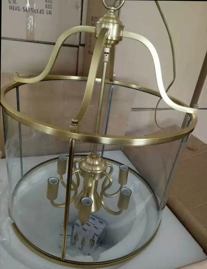 Vintage brass pendant light with clear glass enclosure and five candle-style sockets helps create warm dining room ambiance