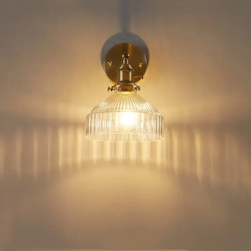 Vintage brass wall lamp with ribbed glass pull chain shade diffusing warm light for living room use