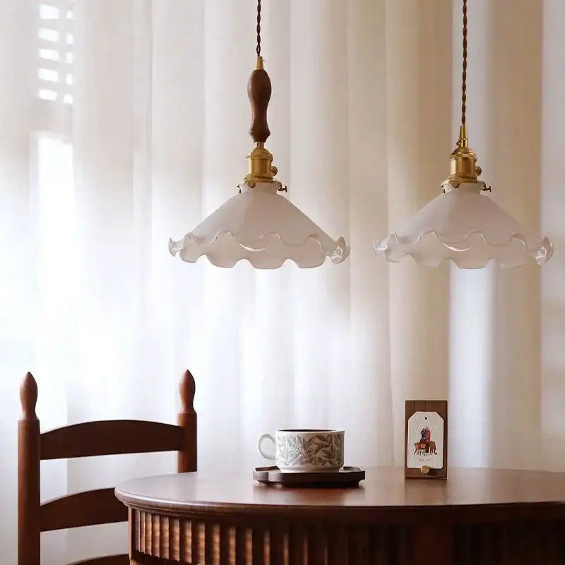 Two vintage brass scalloped glass led pendant lamps with frosted shades hang from twisted brown cords for bedroom lighting