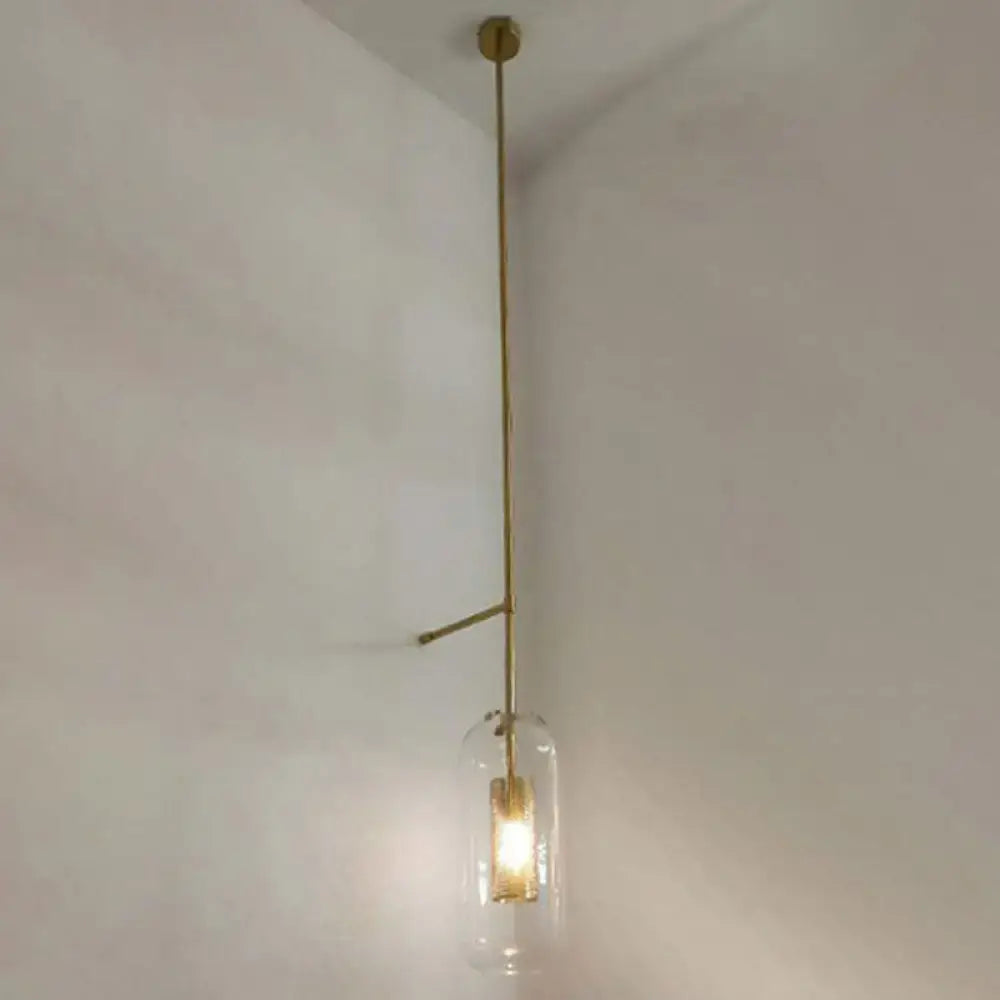 Minimalist vintage brass wall lamp with a clear glass cylinder shade and exposed bulb for living room sconce lighting
