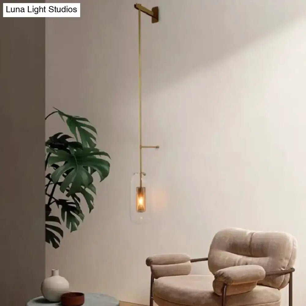 Vintage brass wall lamp with gold-toned minimalist arm and clear glass cylinder shade for living room sconce
