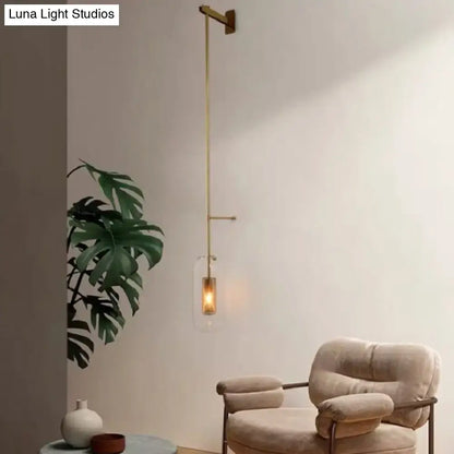 Vintage brass wall lamp with gold-toned minimalist arm and clear glass cylinder shade for living room sconce
