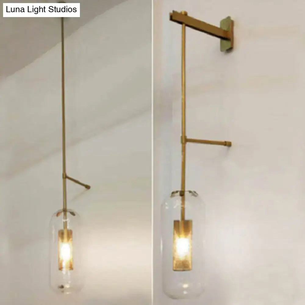 Vintage brass wall lamp with clear glass cylinder shade and illuminated rectangular bulb for living room use