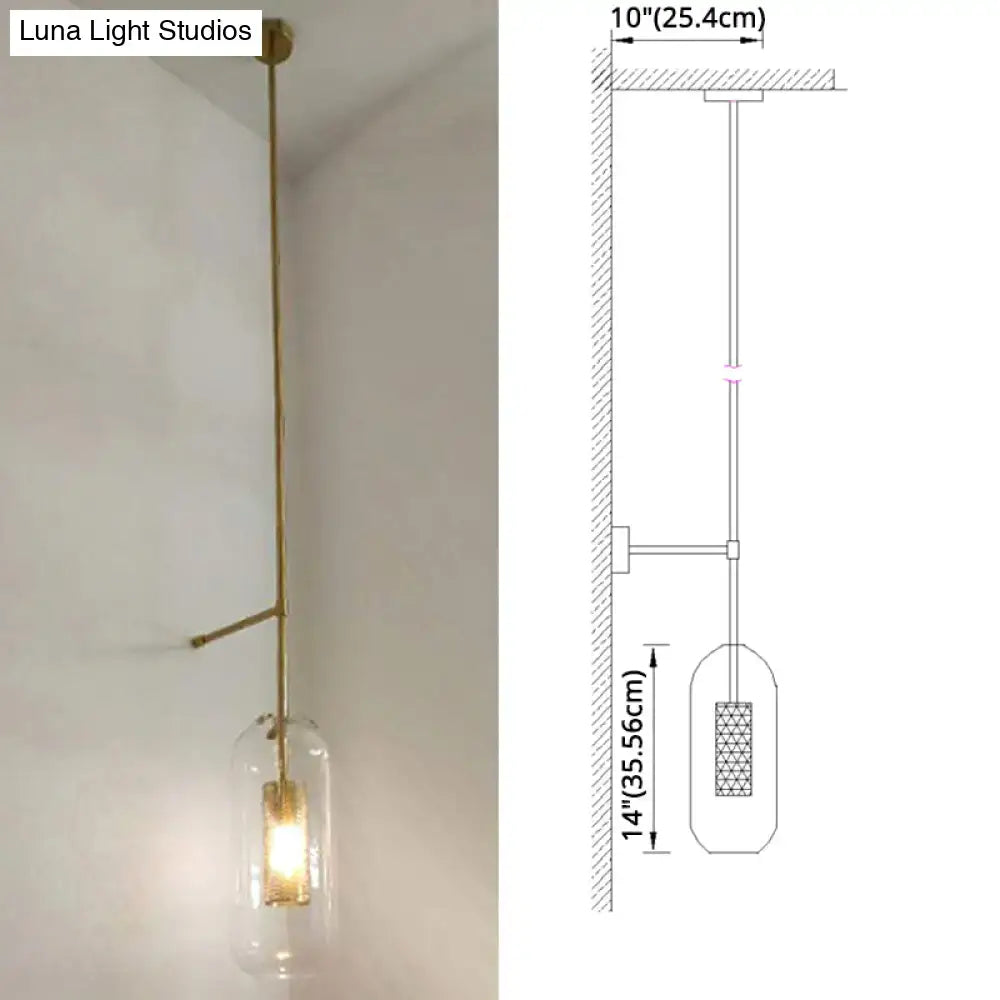 A vintage brass wall lamp with a clear glass cylinder shade housing an illuminated bulb for living room use
