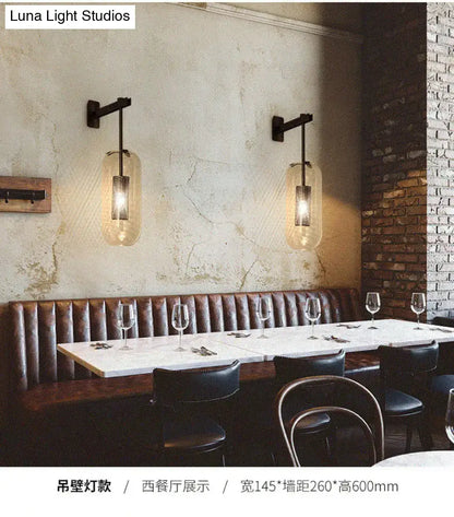 Black metal wall sconce with translucent amber glass cylinder shade for vintage brass wall lamp living room use