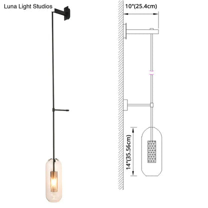 Black metal wall sconce with a brass wall lamp design and a clear glass cylinder shade housing an illuminated bulb