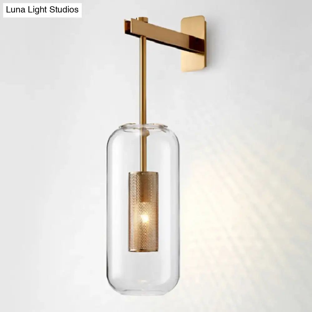 A modern brass wall lamp with a clear glass cylinder and textured glass cylinder shade for living room use