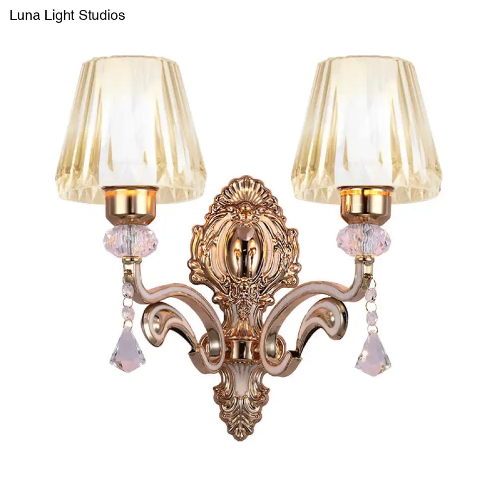 Vintage brass wall lamp with gold-toned ornate design and fluted amber glass shades featuring dangling pink crystals