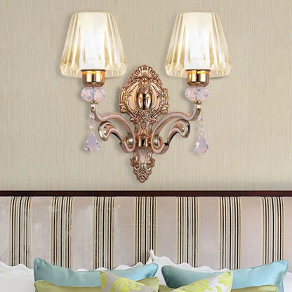 Ornate rose gold wall lamp with clear glass shade featuring two cream fluted shades and lavender crystal droplets