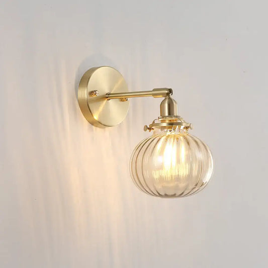 Vintage brass wall light with champagne clear ribbed glass shade and exposed filament bulb for bedroom use