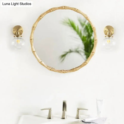 Round mirror with bamboo-inspired gold frame paired with vintage brass wall light featuring champagne clear glass shade