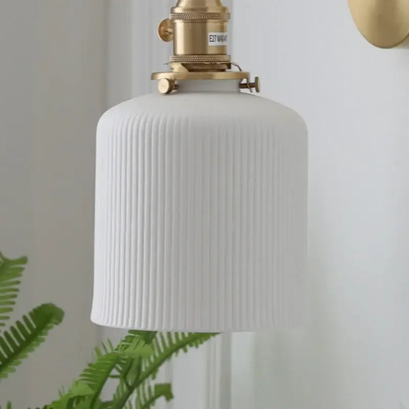 Vintage brass wall light with white ribbed ceramic pendant and knob switch featuring decorbites ceramic knob design