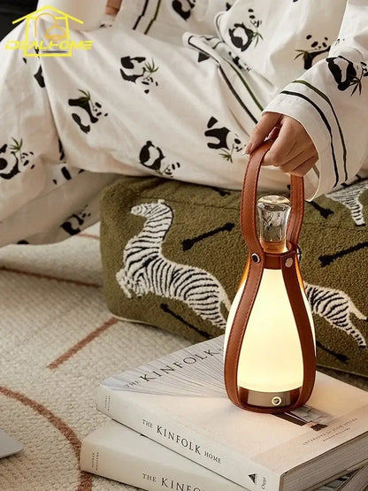 A warm softly glowing vintage brown leather grapefruit table lamp with glass bottle body and portable handle decorbites table lamp