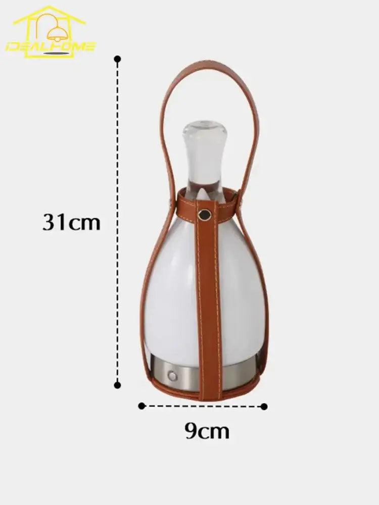 A sleek white glass grapefruit table lamp with clear stopper encased in tan leather strap and metal base decorbites table lamp